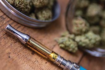 ST-Cannabis Oil Vape Pen Close-up On Wood